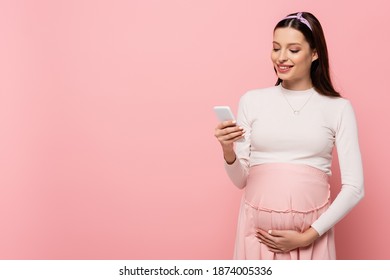 happy young pretty pregnant woman using smartphone isolated on pink - Powered by Shutterstock