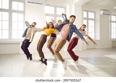 Happy young professional hip hop dancers practice moves in studio together. Smiling active millennial group dance prepare for concert. Youngsters moving to music. Subculture and hobby concept. - Powered by Shutterstock