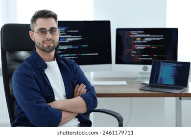 Happy young programmer working at desk in office