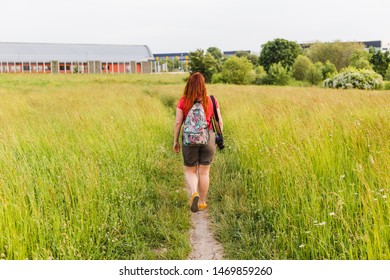 Happy Young Redhead Woman With Backpack And Camera Walks Out Of Town. Travel And Turist Concept.