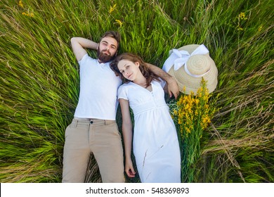 Happy Young Relaxed Couple In Love Laying Down On The Grass Overhead
