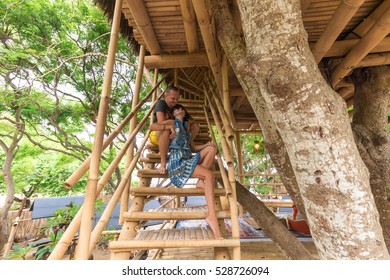 Happy Young Romantic Caucasian Couple In Gazebo On The Tree, Tropical Bali Island, Indonesia.. Vacation Honeymoon Getaway.