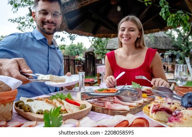 Happy young romantic couple having lunch or dinner in a beautiful open air country restaurant with traditional food. Front focus on a plate with cheese. - Shutterstock ID 2208058595