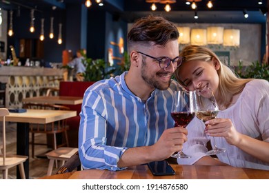 Happy Young Romantic Couple In Love, Toasting With Wine Glasses At Dinner In A Beautiful Restaurant. Copy Space.