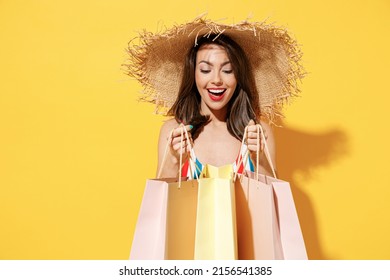 Happy young sexy woman slim body wear striped red blue swimsuit straw hat hold package bags after shopping isolated on vivid yellow color background studio. Summer hotel pool sea rest sun tan concept