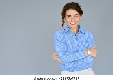 Happy young smiling confident professional business woman wearing blue shirt, pretty stylish female executive looking at camera, standing arms crossed isolated at gray background, portrait.