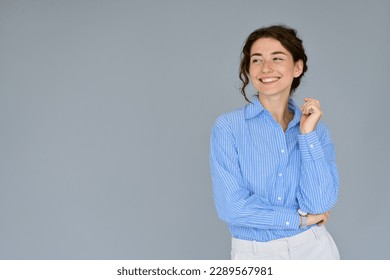 Happy young smiling professional business woman wearing blue shirt looking away interested in ads at copy space presenting advertising promotion standing isolated at gray background. - Shutterstock ID 2289567981