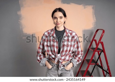 Happy young smiling woman painting walls in her new house, looking at camera with hands in pockets. Renovation, redecoration and repair concept. [[stock_photo]] © 
