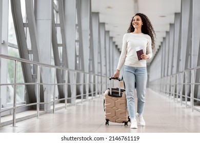 Happy Young Smiling Woman Walking With Luggage At Airport Terminal, Cheerful Middle Eastern Female Holding Passport With Tickets And Carrying Suitcase While Going To Flight Departure Gate, Copy Space - Shutterstock ID 2146761119