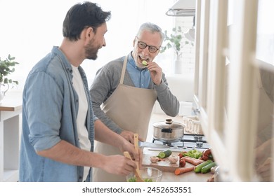 Happy young son helping his old elderly senior father in the kitchen to cook prepare meal, dinner, lunch for family. Happy father`s day! I love you, dad! Men cooking together - Powered by Shutterstock