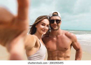 Happy young sport couple taking a selfie by smartphone at the seaside. Healthy man and woman friend take photograph together after workout at the beach - Powered by Shutterstock