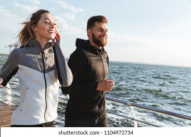 Happy young sports couple jogging together at the beach - Powered by Shutterstock