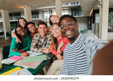 Happy young students taking a selfie portrait together at university library. African american guy shooting a photo with his smiley classmates on a high school meeting. Friends at academy. friendship - Powered by Shutterstock