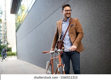 Happy young stylish businessman going to work by bike