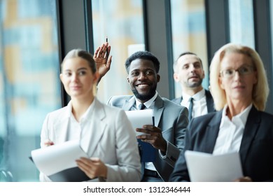 Happy Young Successful Businessman In Suit Raising Hand To Voice His Viewpoint To Speaker At Seminar