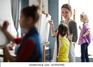 Happy Young Teacher Mentoring Group Of Kids In Studio Of Arts