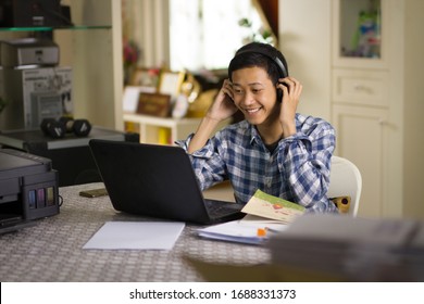 Happy Young Teenage Of Asian Boy Learning Language, Look At Laptop Camera During Chat Conference With Smiling Face At Home Office.