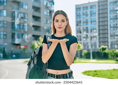 Happy young teenage female with red hair backpack making air kiss gesture - Powered by Shutterstock