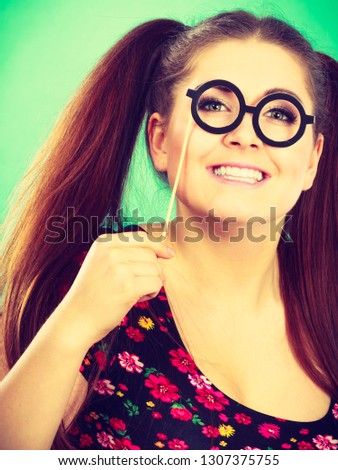 Happy young teenage woman holding fake eyeglasses on stick having fun. Photo and carnival funny accessories concept.