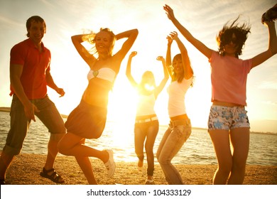 Happy Young Teens Dancing At The Beach On  Beautiful Summer Sunset