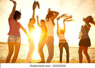 Happy Young Teens Dancing At The Beach On  Beautiful Summer Sunset