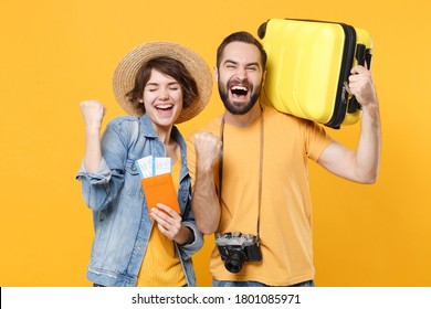 Happy Young Tourists Couple Friends Man Woman Isolated On Yellow Background. Passenger Traveling Abroad On Weekends. Air Flight Journey Concept. Hold Passport Tickets Suitcase Doing Winner Gesture