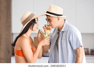 Happy young tourists couple with glass of mojito in kitchen - Powered by Shutterstock