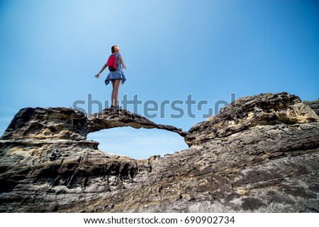 Happy young traveler woman with red hat and bag standing on stone on the mountain.hot sun.