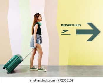 Happy Young Traveler Woman Walking With Suitcase And Music Headphone In Airport, Face Looking Up And Smiling, Departures Sign As Background, Full Length, Side View