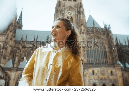 happy young traveller woman in yellow blouse and raincoat in Prague Czech Republic sightseeing.