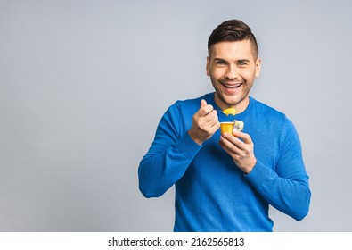 Happy Young Ukrainian Handsome Man Eating Yogurt Isolated Over Grey White Background. Healthy Lifestyle Concept.