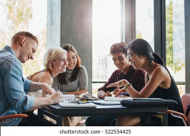 Happy young university students studying with books in library. Group of multiracial people in college library. - Shutterstock ID 522554425
