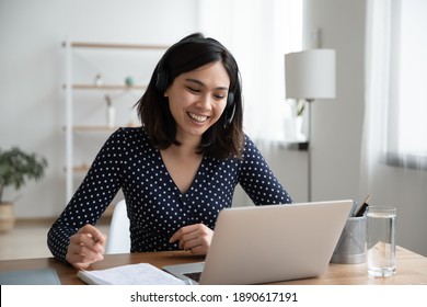 Happy Young Vietnamese Korean Woman In Headset With Microphone Involved In Educational Video Call Conference Conversation, Studying Remotely, Consulting With Teacher Using Computer Application.