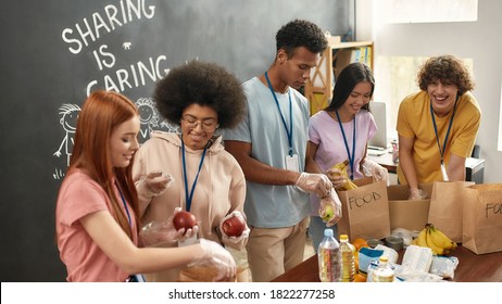 Happy young volunteers group collecting, sorting food in paper bags, Diverse team working together on donation project in charitable organization office, Selective focus, Web Banner - Powered by Shutterstock