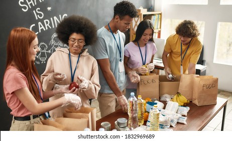 Happy young volunteers group collecting, sorting food in paper bags, Diverse team working together on donation project in charitable organization office, Selective focus, Web Banner - Powered by Shutterstock