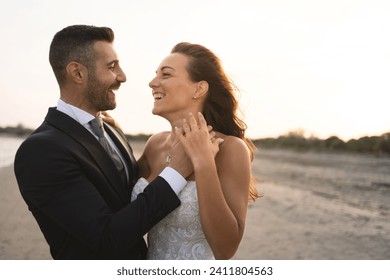 Happy young wedding couple portrait outdoors having fun on the beach looking each others.  - Powered by Shutterstock