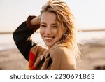 Happy young white woman smiling while walking by seashore on sunny day