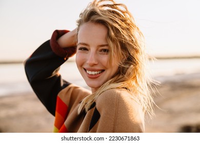 Happy young white woman smiling while walking by seashore on sunny day - Powered by Shutterstock