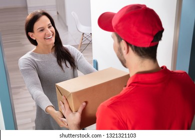 Happy Young Woman Accepting Cardboard Box From Delivery Man