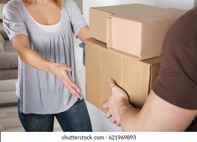 Happy Young Woman Accepting Parcel Box From Delivery Man