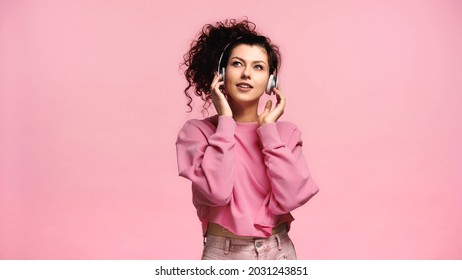 happy young woman adjusting headphones while listening music isolated on pink - Powered by Shutterstock