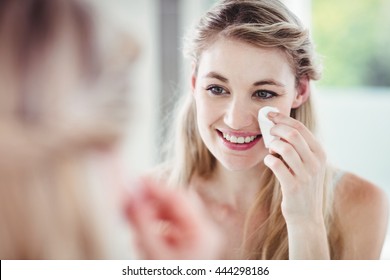 Happy Young Woman Applying Blush While Looking In Mirror