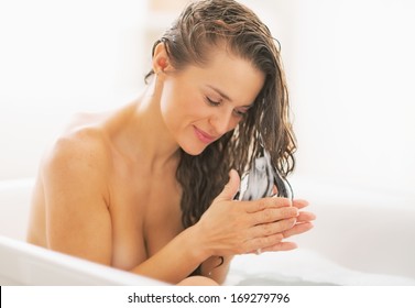 Happy Young Woman Applying Hair Conditioner In Bathtub