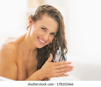 Happy Young Woman Applying Hair Conditioner