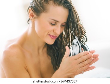 Happy young woman applying hair conditioner in bathtub - Shutterstock ID 674437357