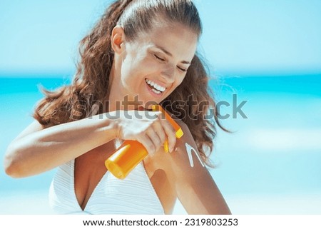 Happy young woman applying sun block creme