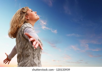 Happy young woman with arms raised towards a blue sky - Shutterstock ID 120133939