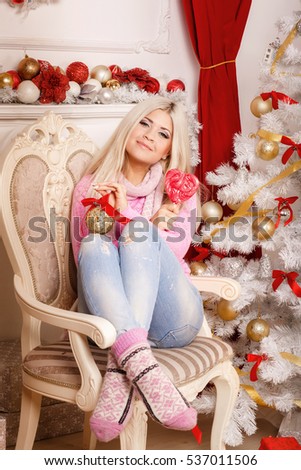 Happy young woman with big candy lollipop and gift boxes at christmas tree - new year home concept. 