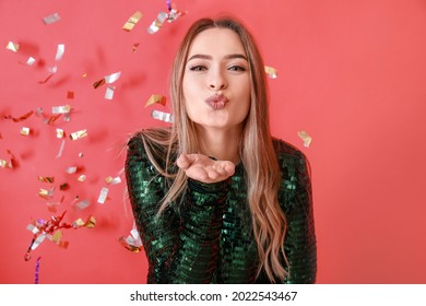 Happy Young Woman Blowing Kiss And Falling Confetti On Color Background