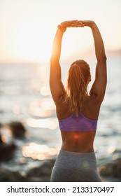 Happy Young Woman Breathing Deep Fresh Air And Raising Arms During Stretching Workout Near The Sea Beach. 